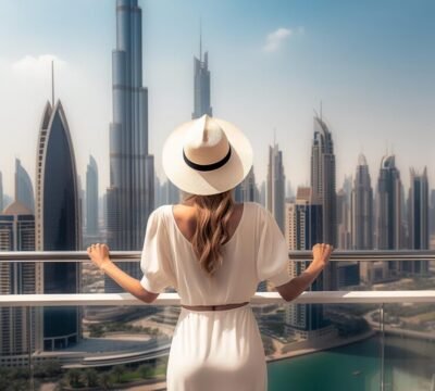 woman-wearing-white-hat-stands-balcony-looks-skyscraper-buildings-city_922357-15675